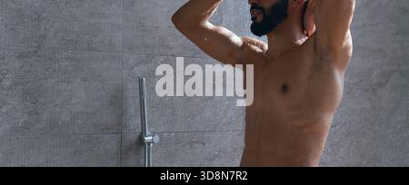 Mann genießt tagsüber eine erfrischende Dusche in einem modernen Badezimmer Stockfoto