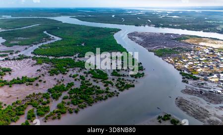 Blick aus der Vogelperspektive auf die gewundenen Wasserstraßen, die durch grüne Mangrovenwälder führen und im Kontrast zur dichten Siedlung entlang der Küste, Port Harcourt, stehen Stockfoto