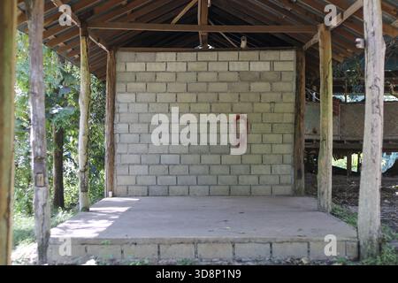 Leere Außenbühne mit rustikaler Holzkonstruktion und Betonblockwand. Einfache, unfertige Konstruktion in natürlicher, ländlicher Umgebung Stockfoto