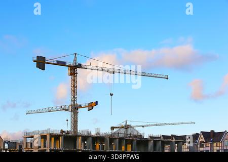 Silhouetten von Turmkränen vor blauem Himmel. Haus im Bau. Stockfoto