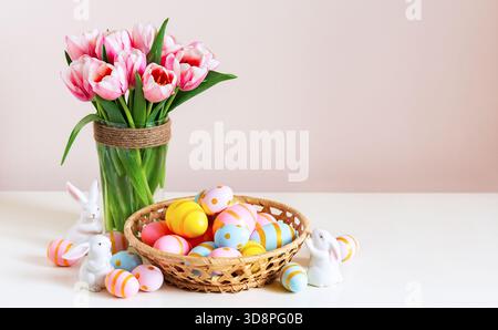 Osterferien dekorieren mit bemalten Eiern im Korb auf Holztisch und schönen Frühlingsblumen. Frohe ostern Hintergrund mit Kopierraum. Stockfoto