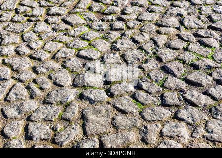 Alter Kopfsteinpflastersteinpflasterperspektive Hintergrund. Pflastersteinpflasterstruktur. Der alte Bürgersteig aus Stein in Rom, Italien. Kopfsteinpflasterpflaster von oben. Stockfoto