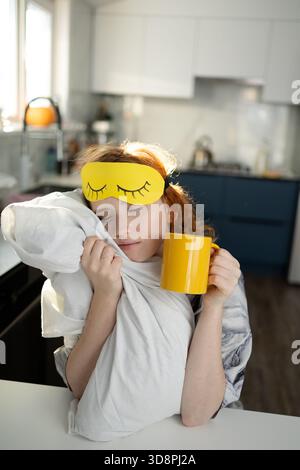 Morgendliches Kaffeereritual, schläfrige Dame genießt warmes Getränk am Morgen, ruhige Morgenszene mit Frau mit Kaffee und Kissen, Frau beginnt ihren Tag friedlich mit einer tröstenden Tasse heißem Kaffee Stockfoto