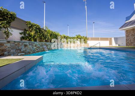 Sprudelnde Wasserstrahlen und Wasserfälle in einem modernen Außenpool Stockfoto