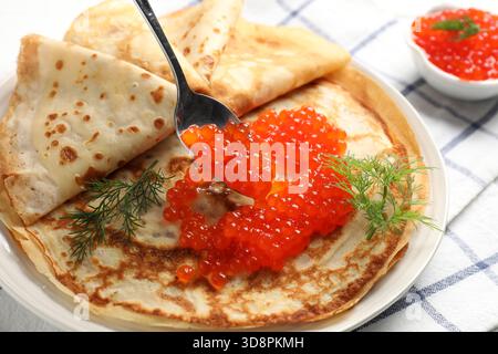 Rote Kaviar auf dünne Kreppchen am Tisch geben, Nahaufnahme Stockfoto
