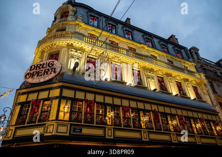 Brüssel, Belgien - 30. November 2025: Das mit festlichen Lichtern und roten Weihnachtsbögen an jedem Fenster erleuchtete Gebäude der Drogenoper während des Winters gewann Stockfoto