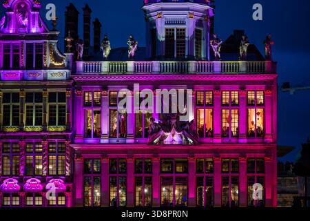 Brüssel, Belgien - 30. November 2025: Leuchtend rosafarbene Beleuchtung der Grand Place guildhall mit kunstvollen Details und warmen Innenbeleuchtung während des Win Stockfoto