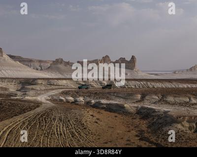 Offroad-suvs durchqueren einen Feldweg über die erodierten weißen Kreidefelsen und die ausgedehnte, trockene Steppe des Ustyurt-Plateaus, die an abgelegene Abenteuer und Entdeckungen erinnern Stockfoto