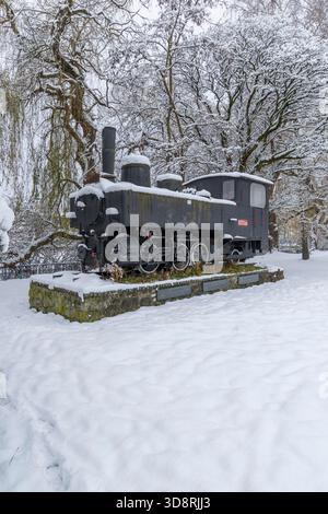 Eine alte Dampflokomotive, die im Winter in einem Bahnhof mit weißem Schnee bedeckt ist Stockfoto