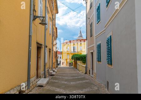 Charmante, enge Straße mit farbenfrohen Gebäuden in einer mediterranen Stadt. Omišalj, Insel Krk, Kroatien. Stockfoto