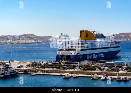 Mykonos, Kykladen, Griechenland - Mykonos New Port, eine Blue Star Ferries Fähre liegt am Kai im neuen Hafen vor der Skyline von Mykonos Town. Stockfoto