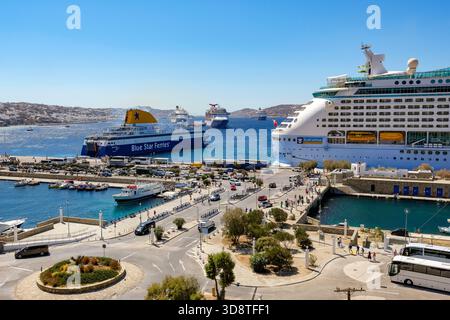 Mykonos, Kykladen, Griechenland - Mykonos New Port, eine Blue Star Ferries Fähre und ein Kreuzfahrtschiff liegen am Kai im neuen Hafen vor dem Skyli Stockfoto