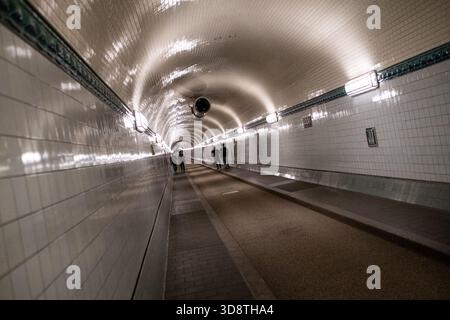 Blick auf Menschen, die im Alten Elbtunnel in Hamburg am 18. Juni 2025 spazieren. Die Szene fängt den historischen Tunnel mit seinen Charakteristika ein Stockfoto