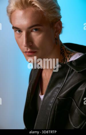 Der hübsche junge Mann zeigt einen trendigen Look und zieht mit seinen auffälligen Details die Aufmerksamkeit auf sich. Stockfoto