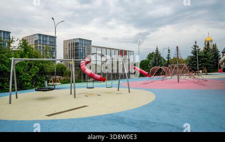 Farbenfroher Spielplatz mit Schaukeln, Rutsche und Kletternetz im Victory Park am Poklonnaya Hill, Moskau, Russland, 10. August 2025 Stockfoto