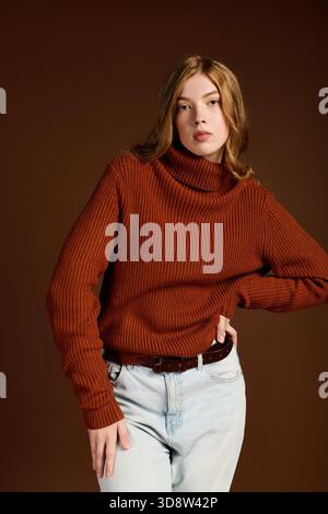 Eine junge rothaarige Frau posiert selbstbewusst in einem gemütlichen Winterpullover. Stockfoto