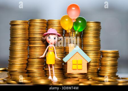 Dream Home Sparkonzept mit Spielzeughaus, Ballons und Figur umgeben von gestapelten Goldmünzen Stockfoto