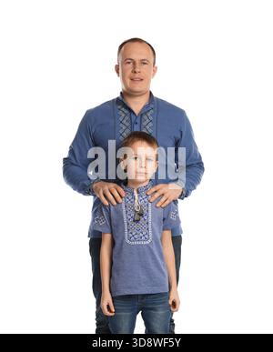 Glücklicher Vater und sein Sohn in bestickten Hemden auf weißem Hintergrund Stockfoto