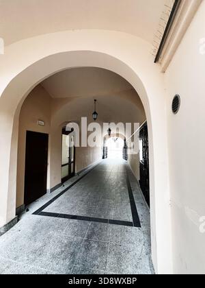 Tarnow, Polen - 25. Oktober 2025: Bogengang mit Lampen und Türen entlang eines beigefarbenen Korridors in Tarnow, Polen. Stockfoto
