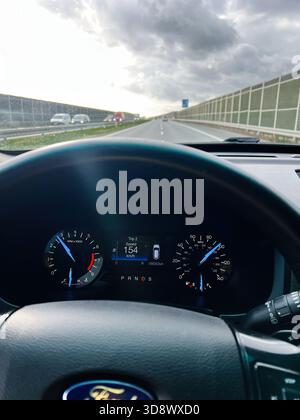 Krakau, Polen - 25. Oktober 2025: Fahreransicht des Armaturenbretts beim Fahren auf einer Autobahn bei bewölktem Himmel, Anzeigen im Fokus. Stockfoto