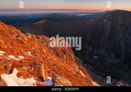 Aus der Vogelperspektive des goldenen Sonnenlichts, das die zerklüfteten Gipfel und Täler küsst und die Landschaft in warmen Farbtönen malte, Pribylina, Region Zilina, Slowakei. Stockfoto