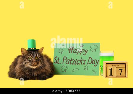 Niedliche Katze in Kobold Hut mit Kalender, Becher grünes Bier und festliche Postkarte für St. Patrick's Day Feier auf gelbem Hintergrund Stockfoto