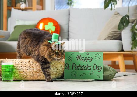 Niedliche Katze im Kobold Hut mit einem Becher grünes Bier und festlicher Postkarte für die Feier zum St. Patrick's Day zu Hause Stockfoto
