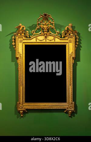 Verzierter goldener Rahmen an einer grünen Wand. Vintage-Modell im luxuriösen Stil mit schwarzem Kopierraum für Porträts oder Kunst. Stockfoto