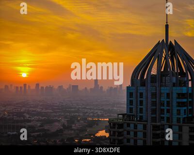 Sonnenuntergang über der Skyline von Dubai, Wolkenkratzer im warmen Abendlicht, urbane Landschaft, moderne Architektur. Drohnenansicht der Golden Hour aus der Luft Stockfoto