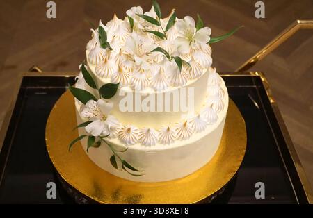 Hochzeitstorte, eine Creme-Torte mit Creme und Blumen auf einem goldenen Tablett. Stockfoto