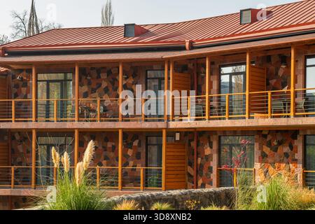 Jerewan Armenien 10.25.2025. Ein großes Gebäude mit rotem Dach und Holzbalkonen. Das Gebäude hat viele Fenster und einen Balkon im zweiten Stock Stockfoto