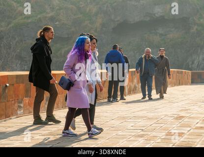 Jerewan Armenien 10.25.2025. Eine Gruppe von Menschen läuft auf einer Brücke, mit einer Frau, die lila Haare trägt. Die Szene ist lässig und entspannt, wie die Menschen es sind Stockfoto