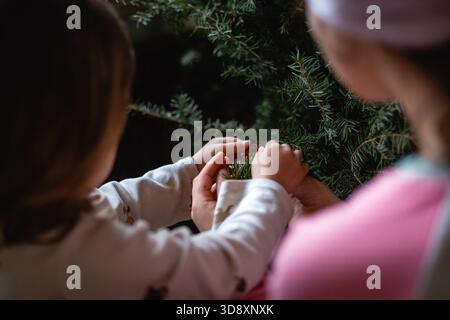 Seltener Blick auf zwei Kinder im Schlafanzug, die den weihnachtsbaum zu Hause schmücken Stockfoto