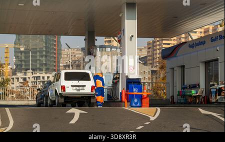 Jerewan Armenien 10.25.2025. Ein Mann betankt ein weißes Auto an einer Tankstelle. Die Tankstelle befindet sich in einer Stadt mit hohen Gebäuden im Hinterland Stockfoto