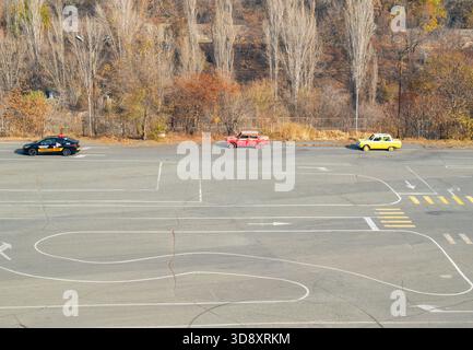 Jerewan Armenien 10.25.2025. Ein Parkplatz mit drei Autos, von denen einer gelb ist. Die Autos stehen in einer Schlange, mit dem gelben Auto in der Mitte. T Stockfoto