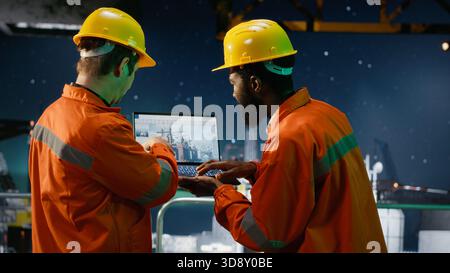Das Team der Umweltbeamten inspiziert die Offshore-Ölplattform unter aurora borealis, wobei ein Laptop verwendet wird, um die Technik der Benzingewinnung zu überwachen. Strategie der Ölproduktion vom Ozean aus. Stockfoto