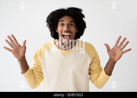 Junger Afroamerikanischer Mann, Der Fröhliche Aufregung Mit Erhobenen Händen Ausdrückt Stockfoto