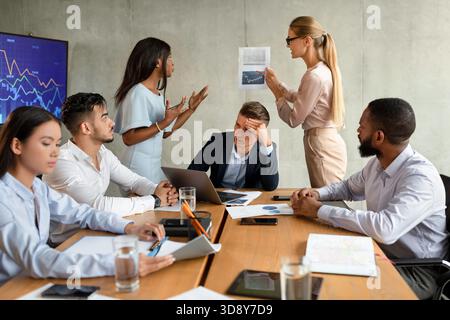 Konflikt zwischen weiblichen Mitarbeitern während der Unternehmensbesprechung im Büro Stockfoto