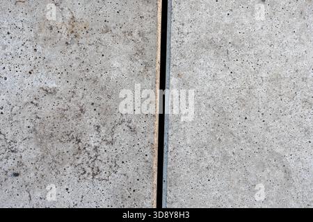 Textur von rauem Beton mit kleinen Poren und einer vertikalen Naht zwischen zwei massiven Betonplatten. Stockfoto