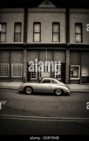 Silberner Porsche 365 im Vintage-Stil, der vor einem alten Gebäude in Sepia-Ton geparkt wurde Stockfoto