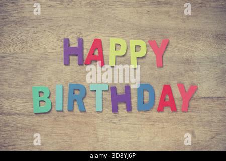 Die bunten Worte HAPPY BIRTHDAY aus Holzbuchstaben auf alten Holzplanken Stockfoto