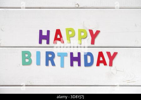 Die bunten Worte HAPPY BIRTHDAY mit Holzbuchstaben auf weißem Brett Stockfoto