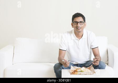 Junger, alleinstehender Indianer, der allein Essen isst, Kopierraum nebenan. Nasi Lemak als Mittagessen. Lebensstil eines Asiaten zu Hause Stockfoto