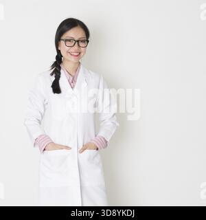 Porträt einer jungen asiatischen Wissenschaftlerin mit Laborkittel auf glattem Hintergrund Stockfoto