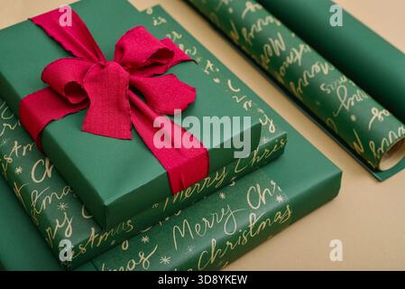 Stapel grüner Geschenkboxen mit rotem Band und goldenem und silbernem sternförmigem Konfetti auf goldenem Hintergrund, Draufsicht Stockfoto