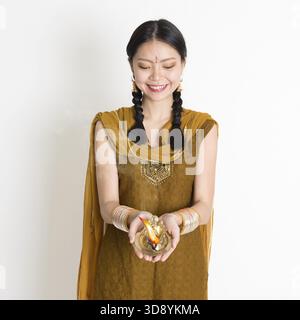 Junge indische Chinesin mit traditionellen Kleidern hält die Diya-Öllampe und feiert Diwali oder deepavali, das lichterfest Stockfoto