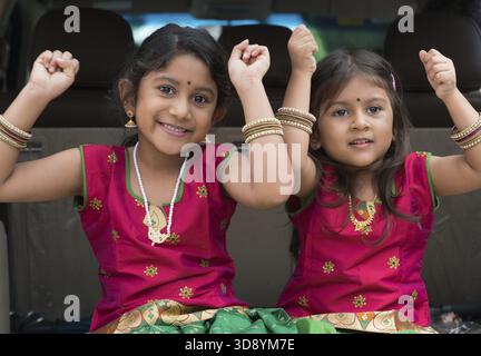 Glückliche indische Mädchen sitzen lächelnd im Auto, bereit für den Urlaub. Asiatische Kinder Stockfoto
