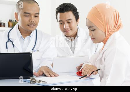 Medizinisches Team diskutiert und arbeitet zusammen. Südostasiatische muslimische Ärzte und Krankenschwestern Stockfoto