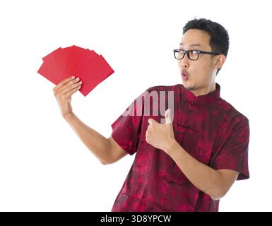 Daumen hoch asiatische chinesische Mann zeigt viele rote Pakete / Ang pow, isoliert auf weißem Hintergrund Stockfoto