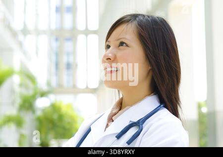 Junge asiatische Medizinstudent lächelnd und wegsehen Stockfoto